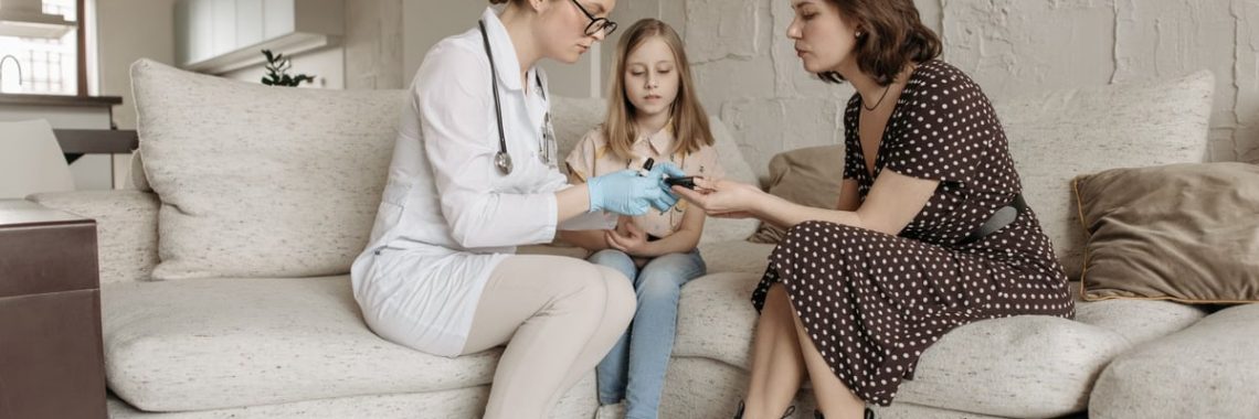 A medical professional examines a child's hand while the mother watches closely.