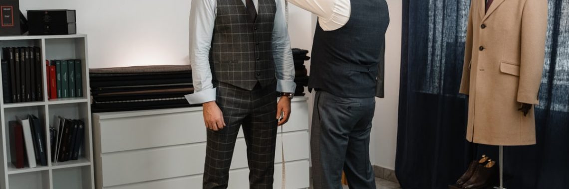Tailor measuring a client's suit for a perfect fit in a stylish fashion studio.
